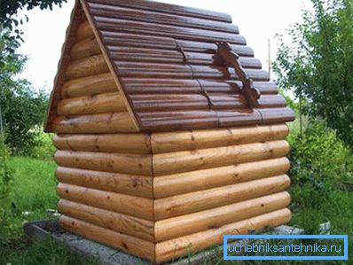 La casa y el pozo en el interior. La combinación de metal (techo de cartón corrugado) y madera (paredes de troncos redondeados) La casa y el pozo en el interior. La combinación de metal (techo de cartón corrugado) y madera (paredes de troncos redondeados)